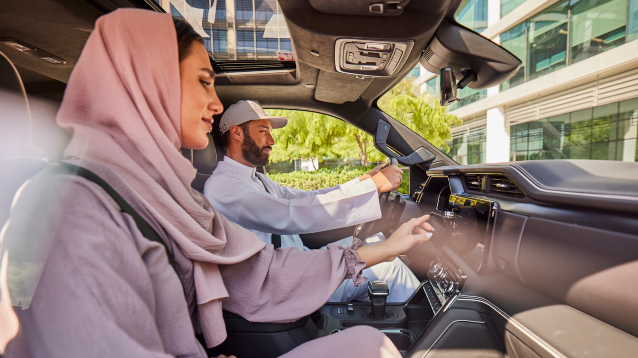 Man and woman inside the car. Woman working on the infotainment
