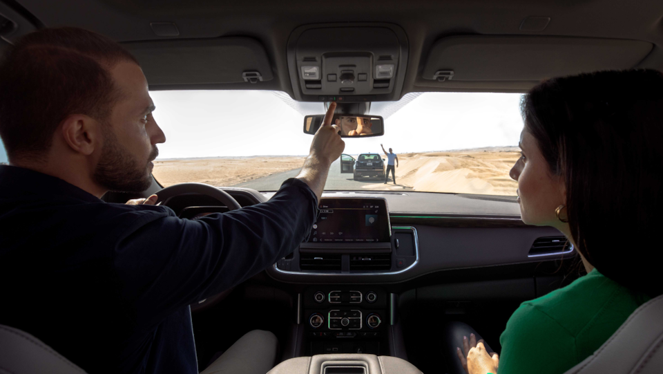 Woman and man sitting in a car pressing the OnStar button